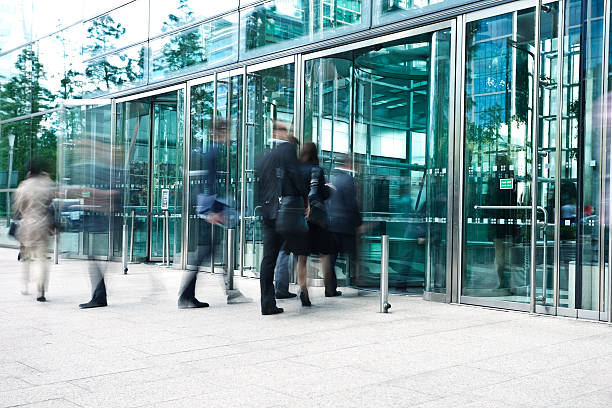 Businesspeople Entering Through Glass Doors of Office Building, Blurred Motion stock photo