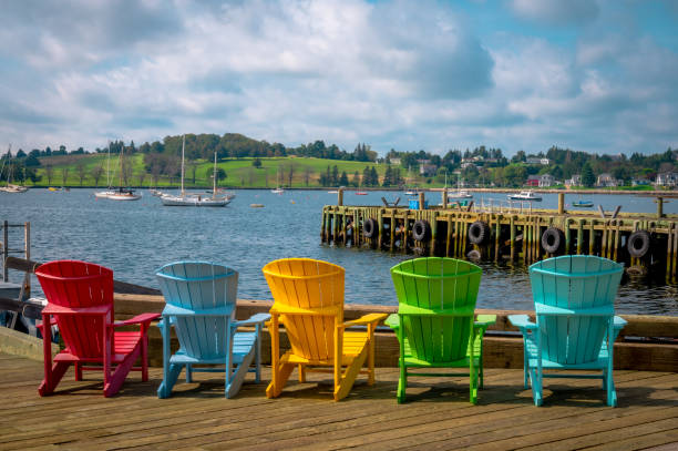 Multicolour Adirondack chairs facing bay, Lunenburg harbour, Nova Scotia, Canada