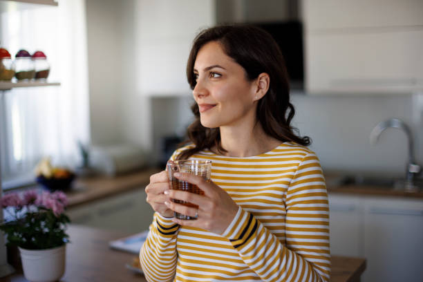 Giovane donna sorridente che gode del tè a casa - foto stock