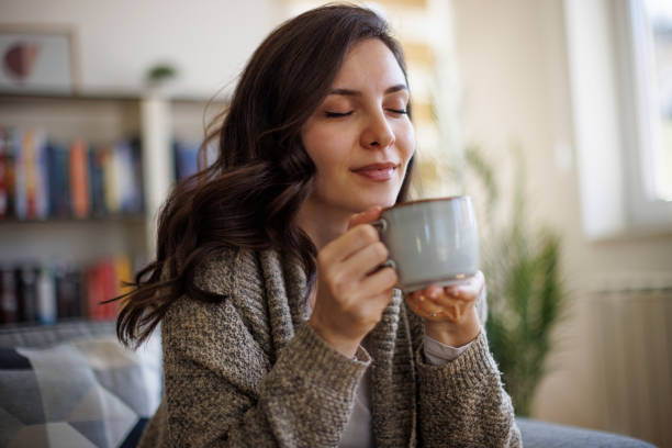 Young smiling woman enjoying in smell of fresh coffee at home stock photo