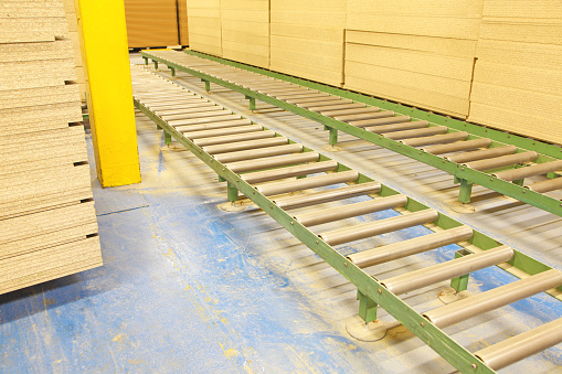 small conveyor belts inside a manufacturing factory making wooden  panels for kitchens and bedrooms