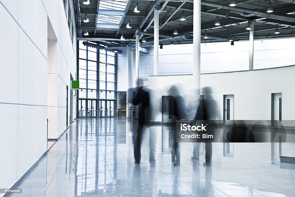 Tres gente de negocios en movimiento borroso caminando en moderno interior - Foto de stock de Andar libre de derechos