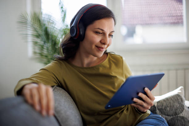 istock Smiling relaxed woman resting on couch using digital tablet 1711589666