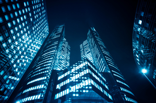 Big glowing windows in modern office buildings at night, in rows of windows light shines.