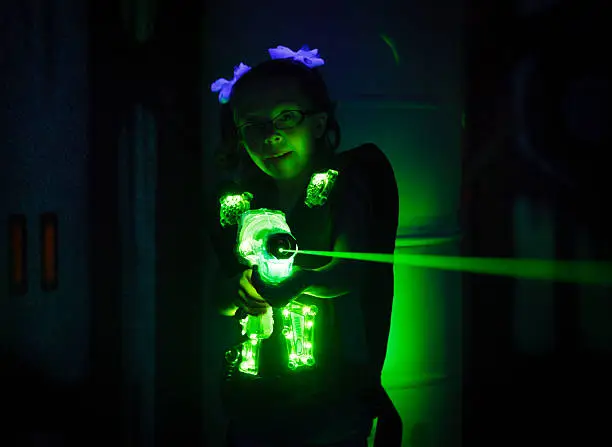 A little girl playing laser tag.  Photographed at a high ISO under black light to capture true look and feel of game.