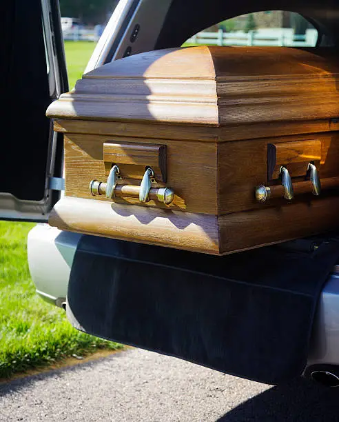 A casket in the back of an open hearse.
