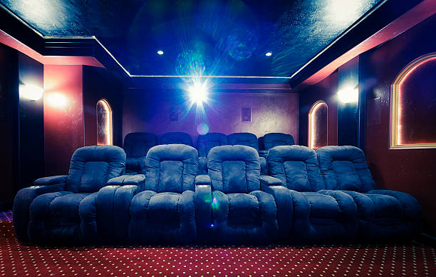 Home Theater Room with Lens Flare A dark home theater room.  Photographed into the projector to create intentional lens flare. entertainment center stock pictures, royalty-free photos & images