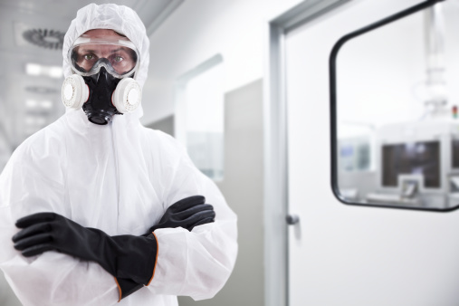 A scary looking scientist wearing a protective suit with goggles and gas mask.