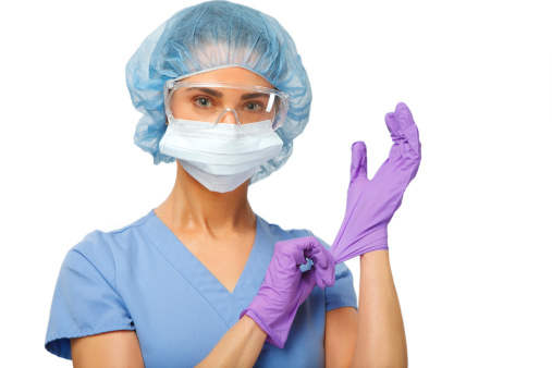 Female nurse in protective medical equipment, looking at camera on white backdrop.