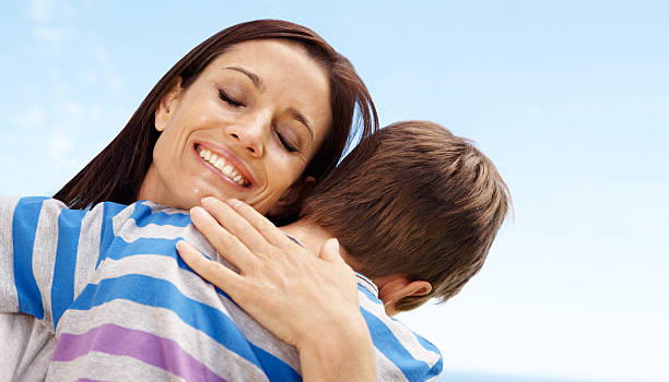 Pretty mother embracing her little boy and smiling