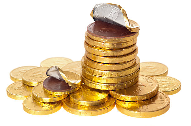 soldi monete cioccolato impilati su bianco - gold pound symbol british currency currency foto e immagini stock