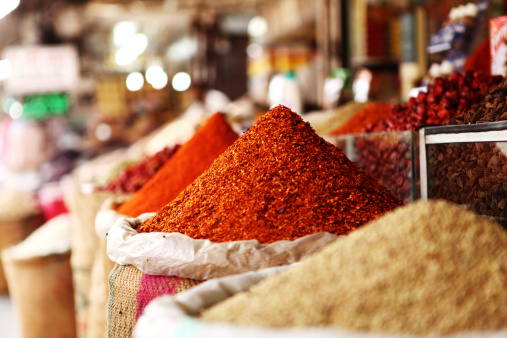 Many colorful, organic, dried, vibrant Indian food, ingredient spices are displayed on an old turquoise-colored ceramic plate background, with atmospheric lighting. Shot directly above, nice color contrast.
