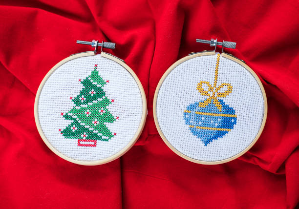 Embroidery hoop with white canvas and two needles placed on vibrant red background, minimalist flat lay symbolizing creativity, traditional craft and artistic inspiration, cross stitch
