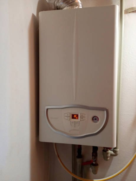 istock A chimney-type wall-mounted boiler for space heating and water heating hangs on the wall. Heating pipes and a gas hose are connected. 1711636069