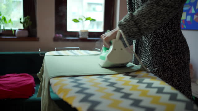 Woman ironing t-shirt at living room