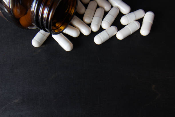 istock White vitamin pills with a jar close-up on a dark background. 1711686008