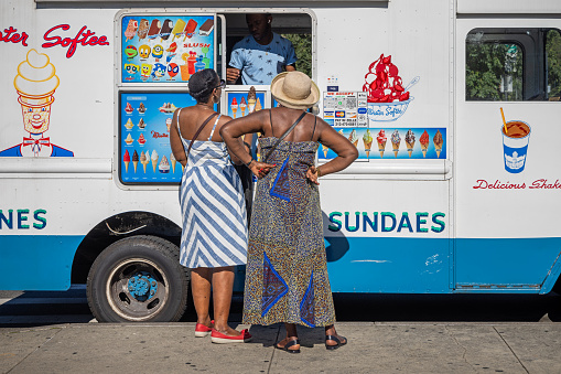 Brooklyn, New York, USA - August 13th 2023: Two mature women outside a van selling ice cream and sundaes on a hot summers day
