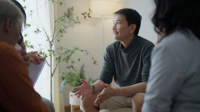 Asian family receives support from female psychologist during group therapy in bright modern office