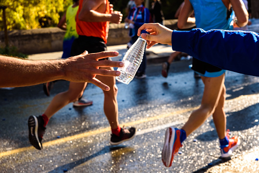 Runner collects a bottle of water to hydrate during a workout.