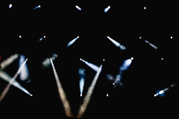 istock Silhouette of some workers illuminated by the spotlights of a stage while checking the limit and the effects of smoke. 1711814320