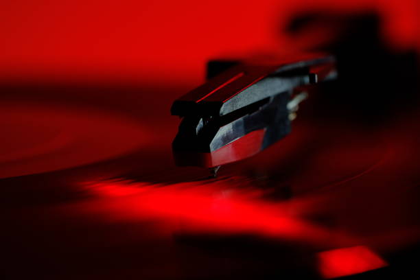 Analog record player under red lighting playing a black vinyl album
