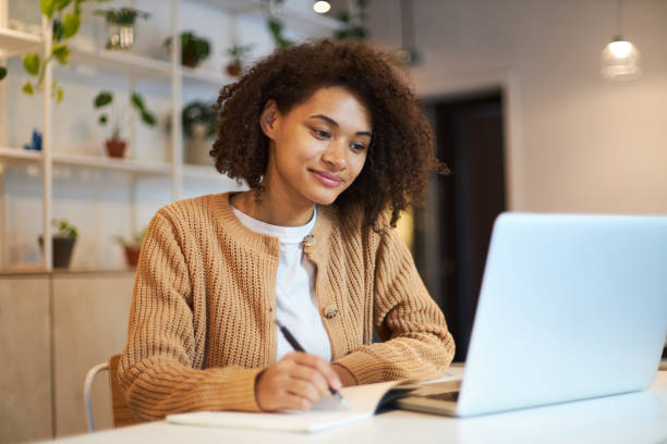istock Confident African American young woman, smart student making notes while watching webinar on laptop 1711858889