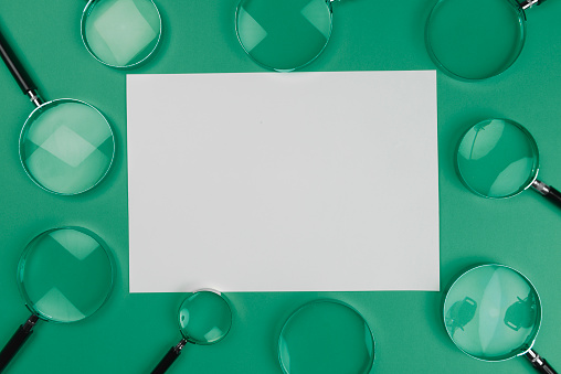 Magnifying glasses on the A4 paper, green background.