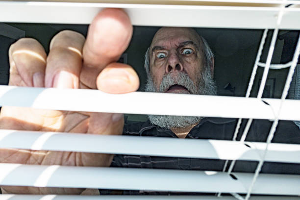 istock Terrified Senior Man Staring Aghast Through Window Blinds 1711867997
