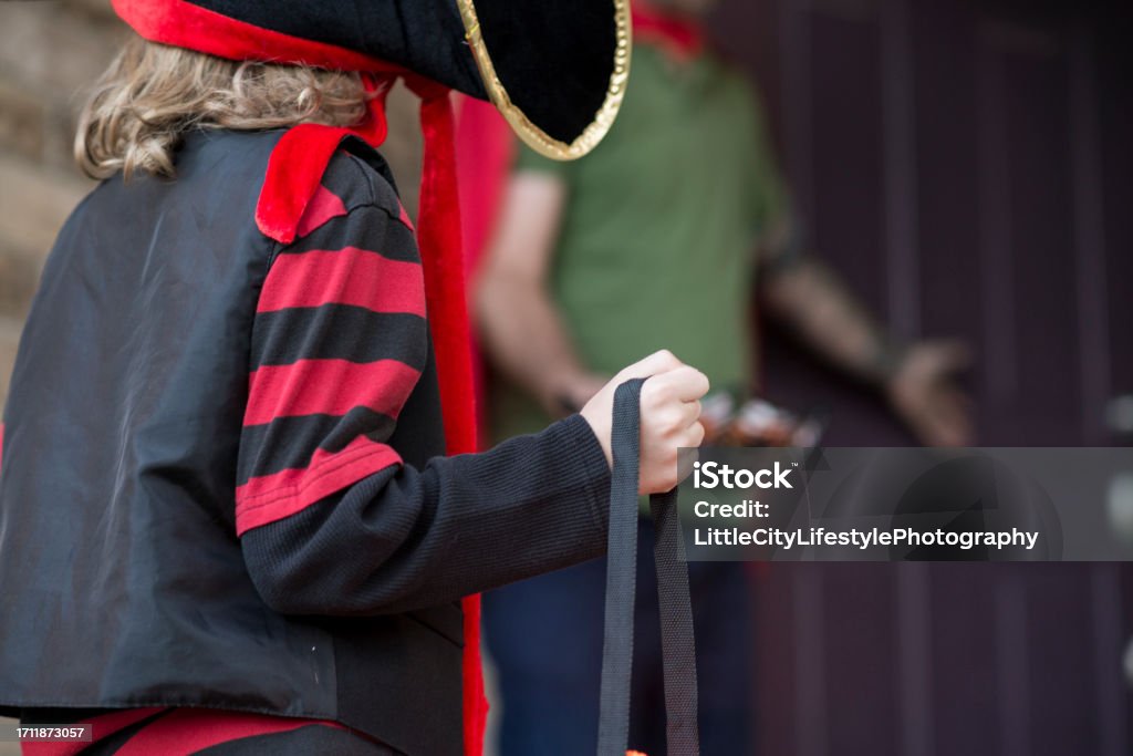 Safe Trick or Treating on Halloween An anonymous young boy in a pirate halloween costume is standing outside of a front door holding his trick or treat bag. An unsafe stranger is gesturing to come into his house. 30-34 Years Stock Photo