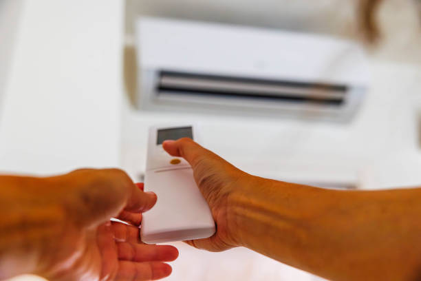 istock A thumb about to press the button while hands holding the remote control of the air conditioner 1711891551