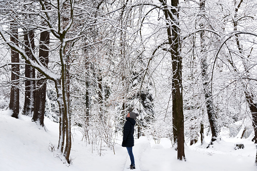 Young woman in snow-covered winter park, forest. Snowy winter. Mindfulness and present moment concept. Love nature concept