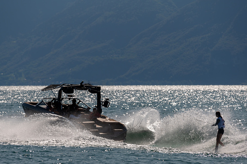 Ouchy, Lausanne, Vaud Canton, Switzerland - 24 September, 2023 : Motorboat with people wakeboarding in Lake Geneva.