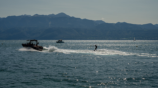 Ouchy, Lausanne, Vaud Canton, Switzerland - 24 September, 2023 : Motorboat with people wakeboarding in Lake Geneva.