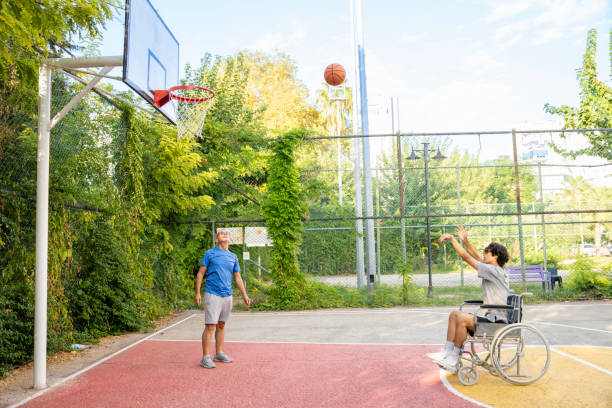 歩行障害のある若い男性と障害のな�い老人が一緒にスポーツをする。 - non moving activity ストックフォトと画像