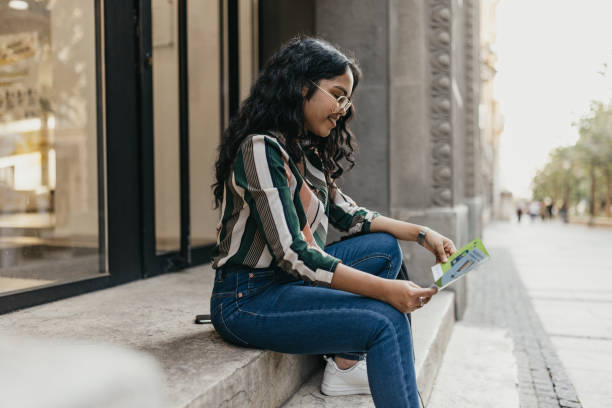 One Indian woman sitting on the steps and reading a leaflet