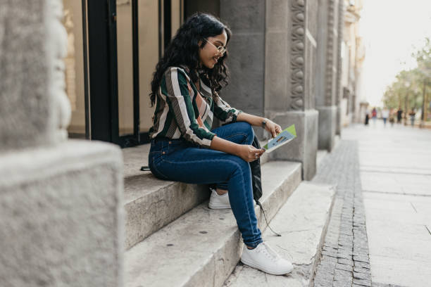 istock One Indian woman sitting on the steps and reading a leaflet 1712008703