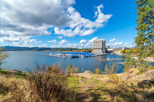 View from a small lakeshore beach on Tubbs Hill, a public park with walking trails, of the lake, marina, city beach and boardwalk at Coeur d'Alene, Idaho USA on a summer day.