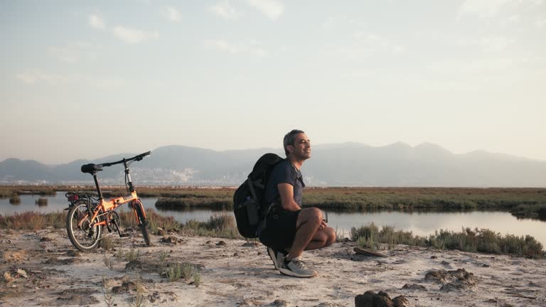 Man flying his drone nearby lake at sunset.