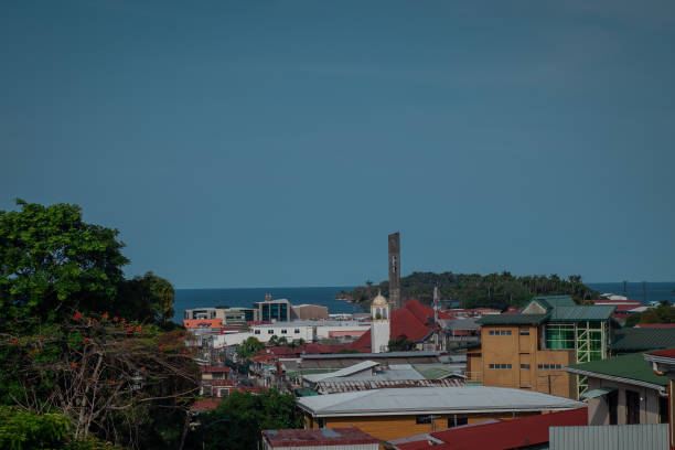Panorama of the city of Limon in Costarica, view from the hill above the city, church and palm trees in the background with visible carribean sea. Panorama of the city of Limon in Costarica, view from the hill above the city, church and palm trees in the background with visible carribean sea. puerto limon stock pictures, royalty-free photos & images