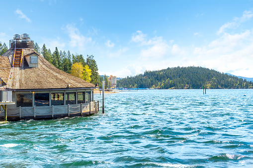 Cedar's Floating Restaurant on Lake Coeur d'Alene with the CDA Resort hotel, marina and Tubbs Hill in view on a Spring day in Coeur d'Alene, Idaho USA.