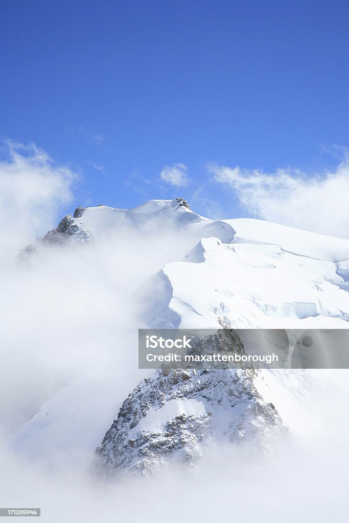 Scenic view of mountain top full of snow Clouds part to reveal the top of a mountain covered in snow. Mont Blanc Stock Photo