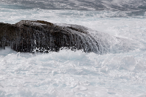 Wave washing over a rock creating milky white foam - zoom for detail