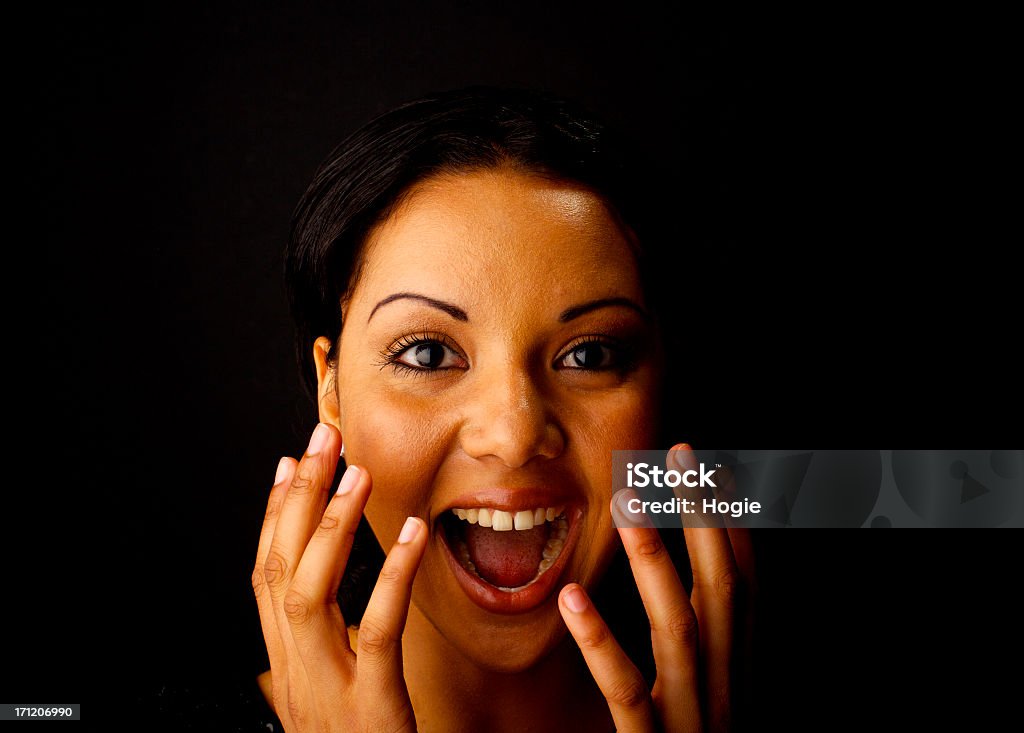 A close-up of a woman with her hands over her face "Attractive, young female on black background." 20-24 Years Stock Photo