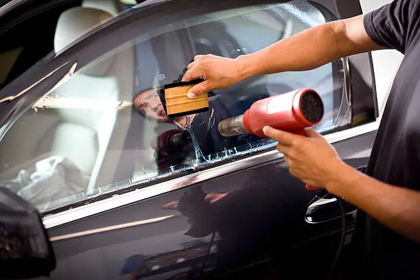 Man installing window tinting on car.