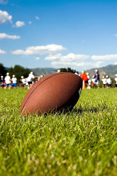 close-up of a football- boys and coaches in background are out of focus