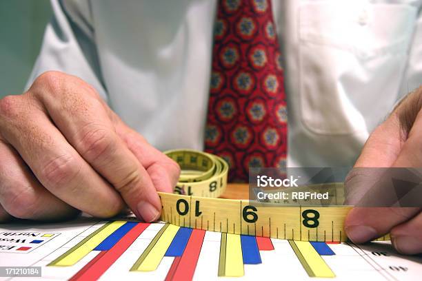 Business Man Holding A Measurement Tape Over Column Charts Stock Photo - Download Image Now