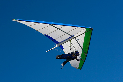 Two people hang-gliding with blue sky in the background
