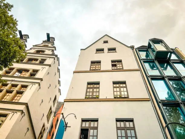 Looking up at contrasting traditional and modern architecture in Cologne, Germany. Located in the central market town square. Set against a fluffy, cloudy sky.
