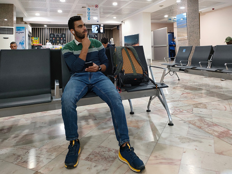 Ouarzazate, Morocco - October 01, 2023: Man in thought using the phone next to his backpack