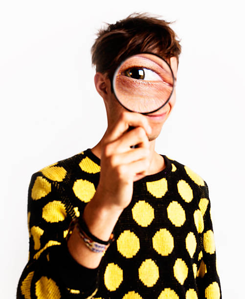 istock Zany young man's eye looks enormous seen through magnifying  glass 171221249